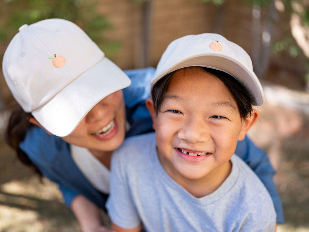 Two kids in Mindful Peach hats laughing