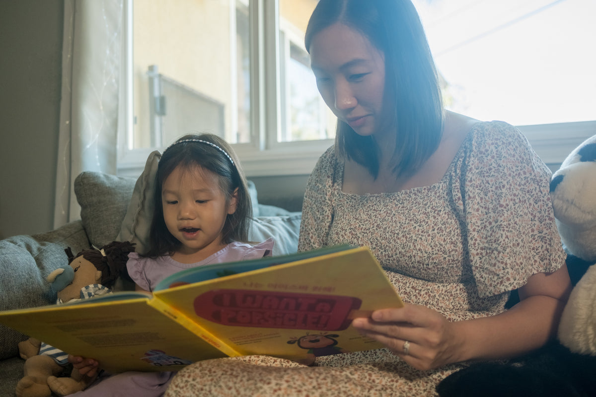 A mom reading a Mindful Peach book with her daughter on the couch